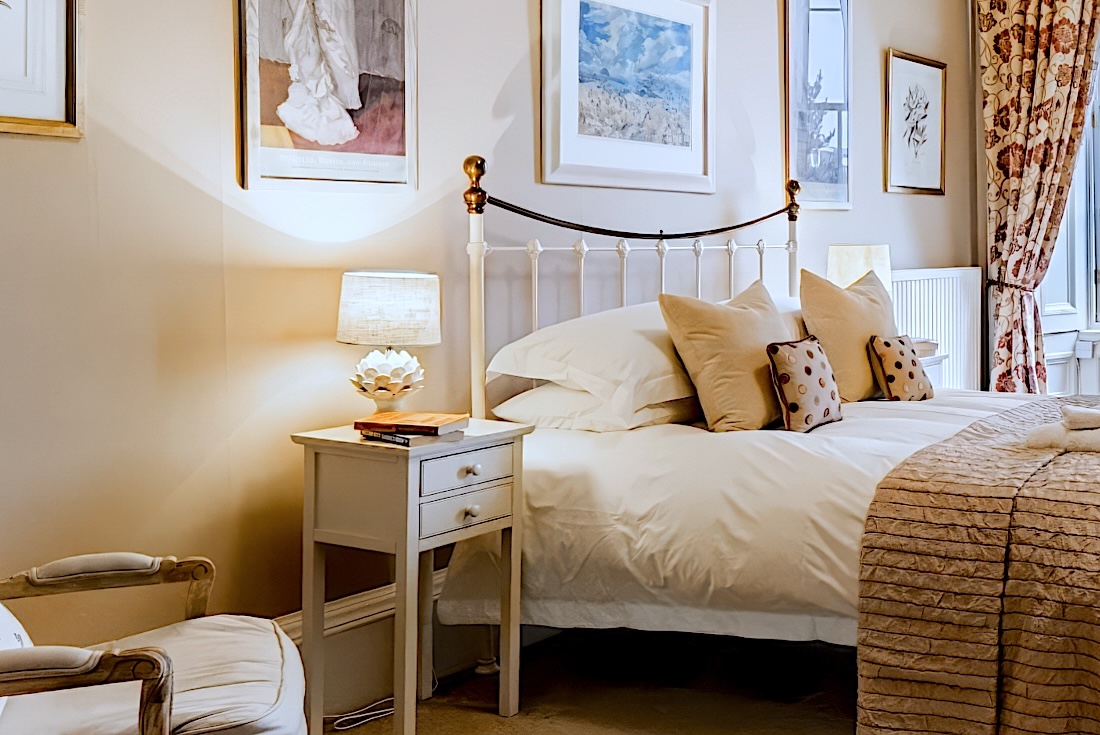 The master bedroom’s iron bedstead with crisp white linen, soft cushions and a bedside lamp