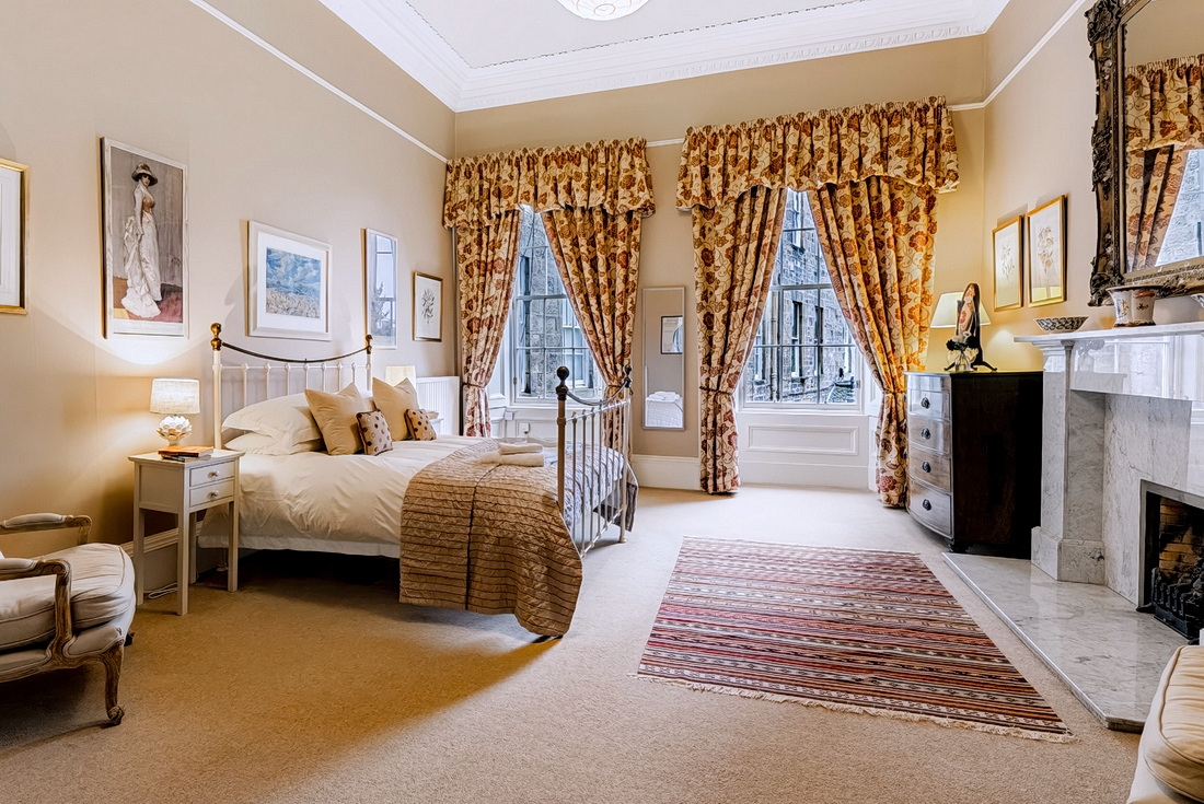 Master bedroom with king-size bed, marble fireplace and French-style armchair