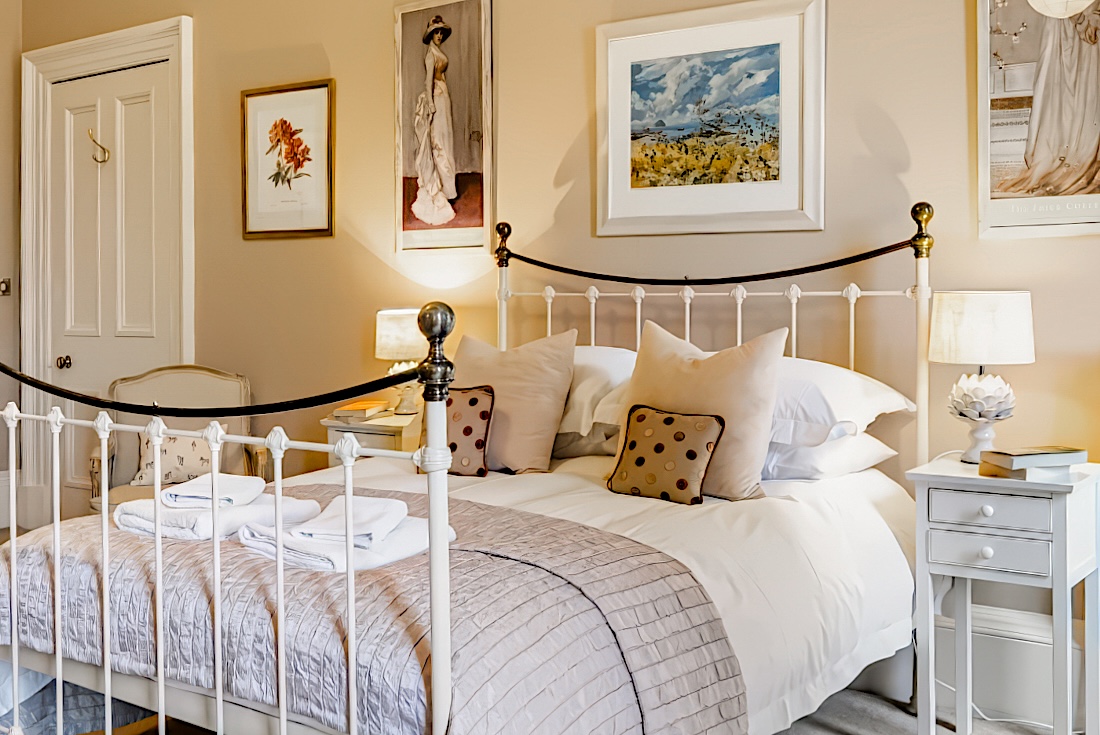 The master bedroom’s king-size iron bed made up with crisp linen and cushions