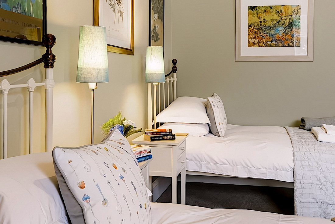 The twin room’s single beds with crisp white linen and pale blue bedside lamps