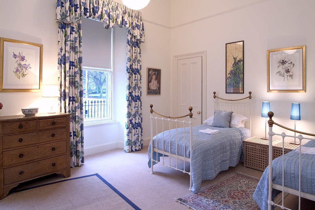 Twin bedroom with two cast-iron single beds and views over public gardens