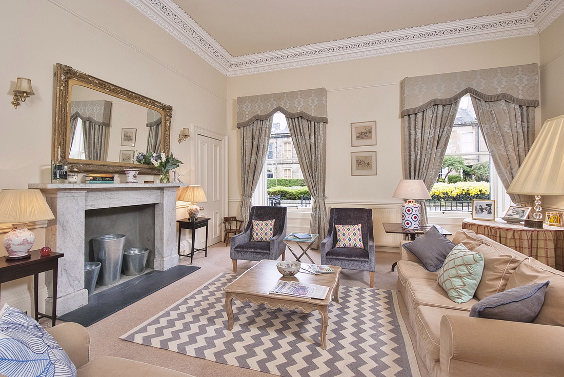 Drawing room with substantial marble fireplace, gilt mirror and two sofas