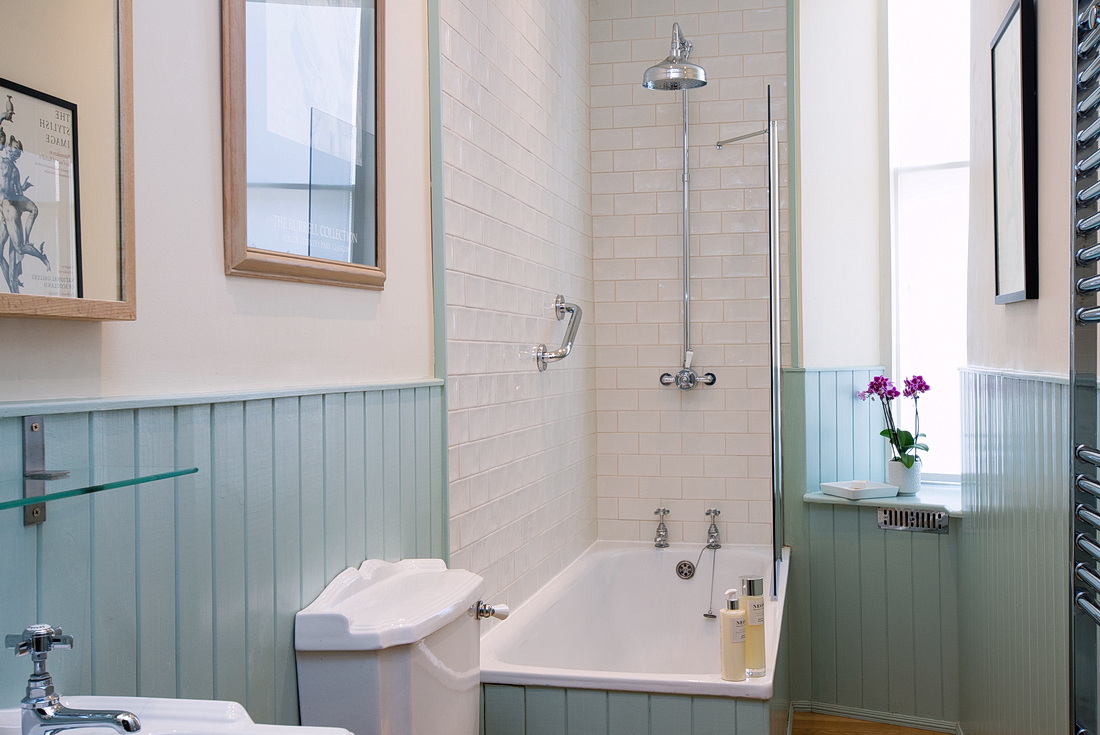 Bathroom with tongue-and-groove panelling, bath with shower and heated towel rails