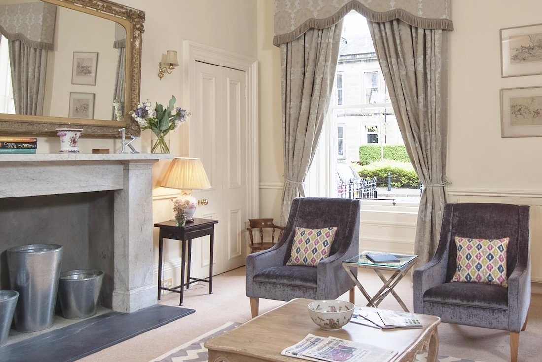 The drawing room’s marble fireplace, gilt mirror and velvet armchairs by the window